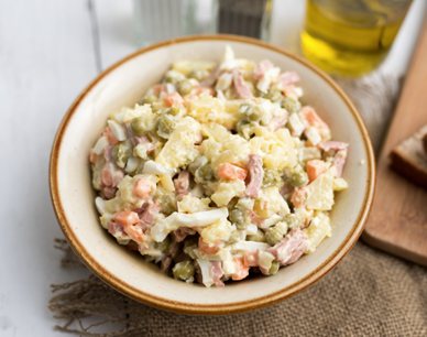 Olivier-Salat mit Kartoffeln, Erbsen, Karotten, Gewürzgurken, Ei und Fleischwurst